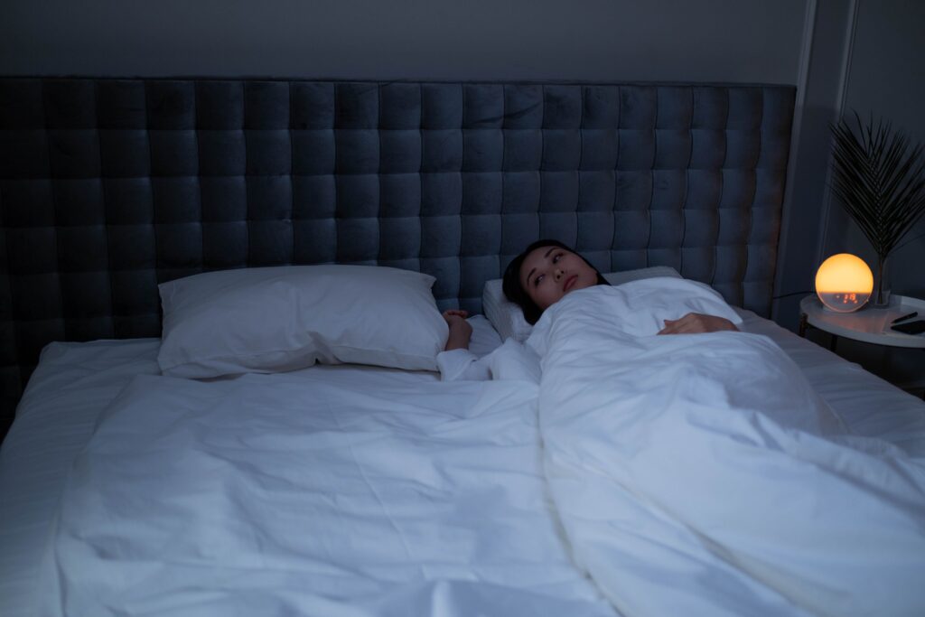 mujer despierta en la cama con dificultad para conciliar el sueño