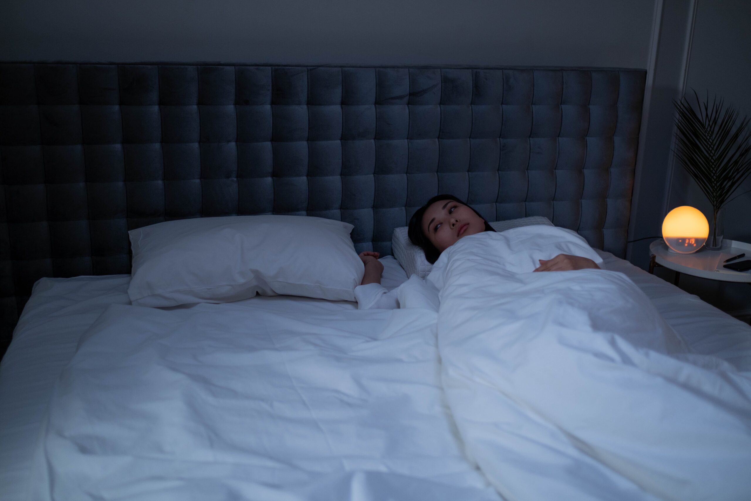 mujer despierta en la cama con dificultad para conciliar el sueño