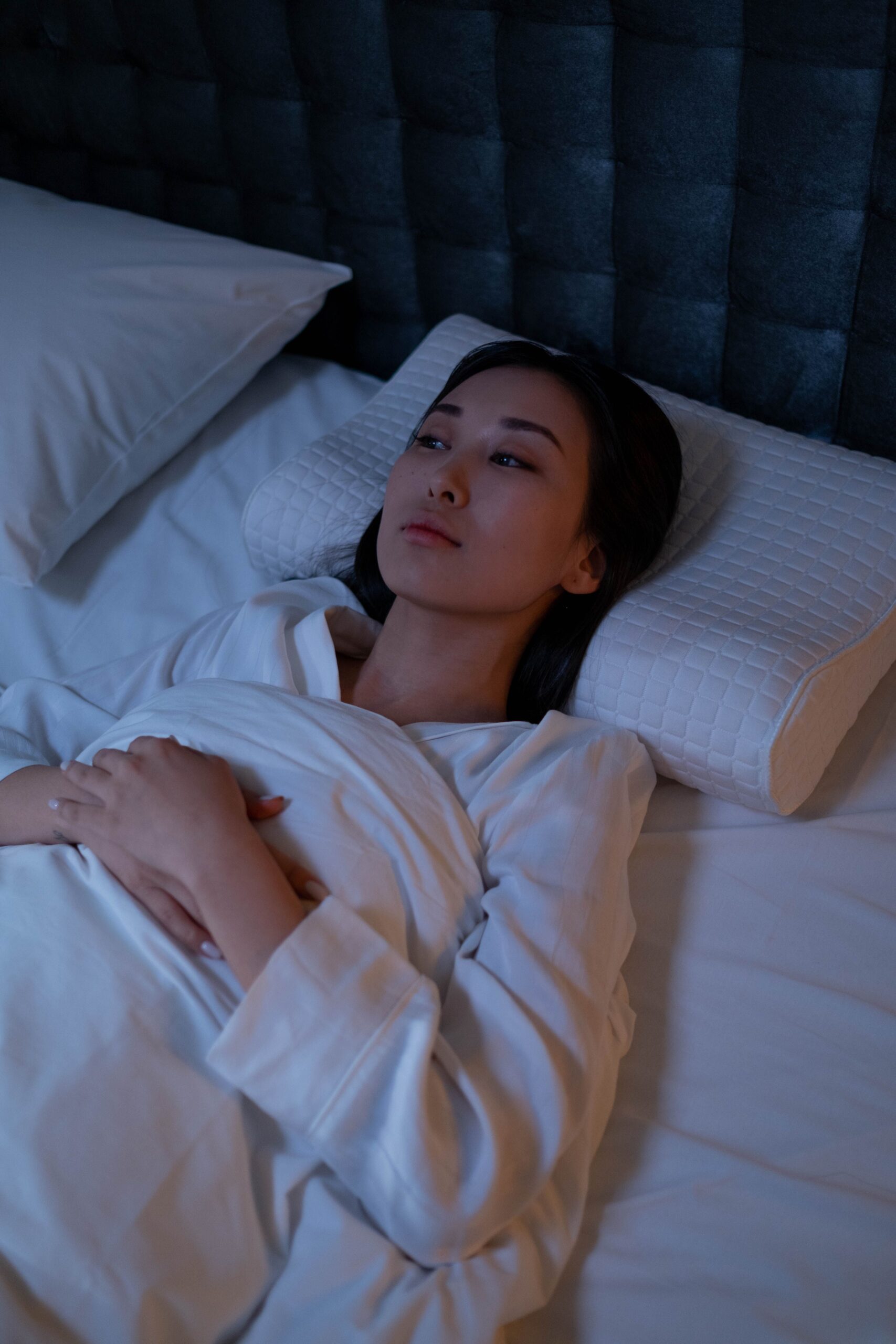 mujer en cama reflexionando sobre la importancia de una almohada correcta