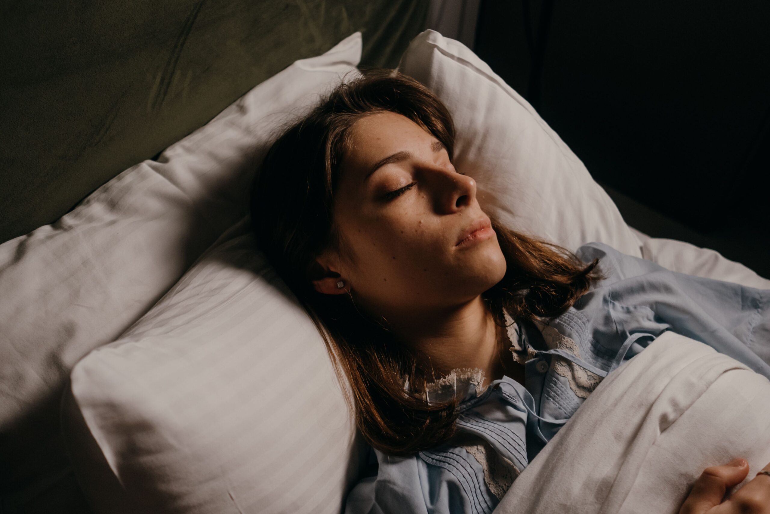mujer durmiendo boca arriba con almohada adecuada en cama blanca