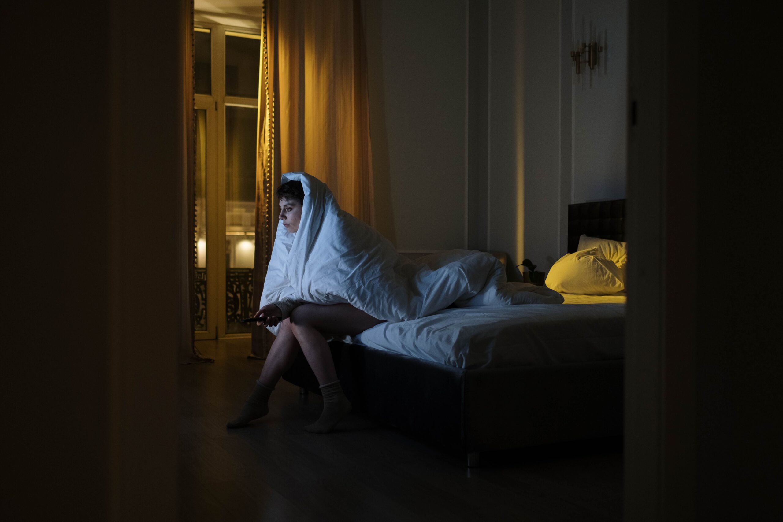 mujer con manta viendo pantalla de noche hábito que impide conciliar el sueño