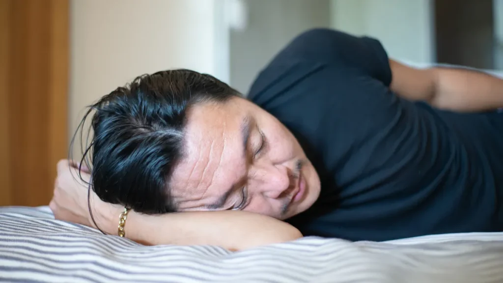 hombre durmiendo boca abajo sin almohada con el brazo bajo la cabeza
