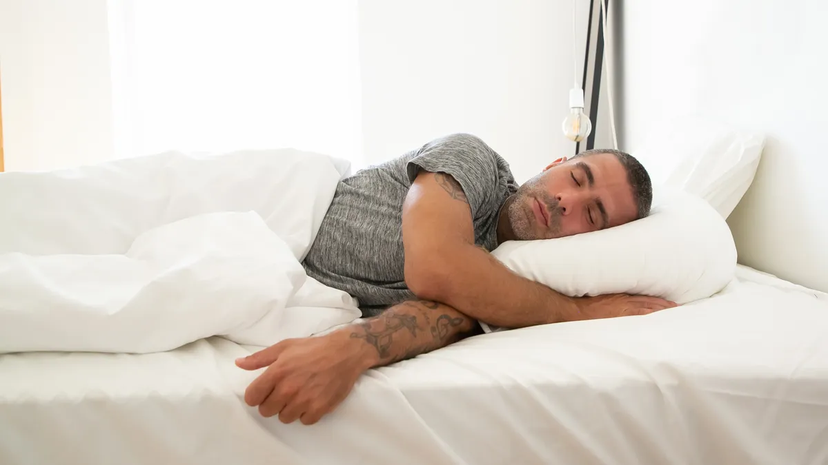 hombre durmiendo de lado sobre una almohada viscoelástica