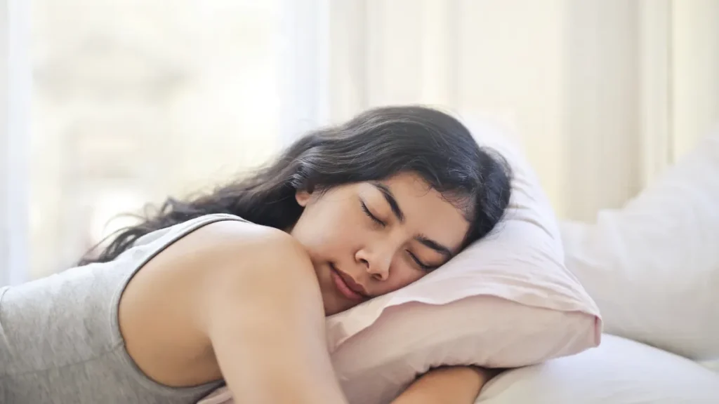 mujer durmiendo boca abajo abrazada a una almohada blanda